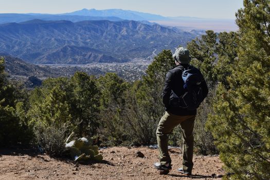 A hiker stands on a mountain saddle staring at distant mountains