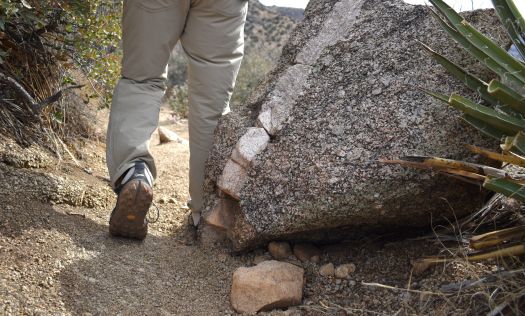 view of the bottom of the Danner N45 hiking shoe as a hiker walks past a granite boulder in the desert