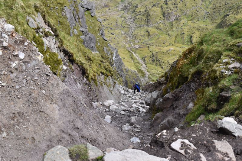 Looking down at a hiker climbing up a steep chute at Ireland's Mt. Carrauntoohil